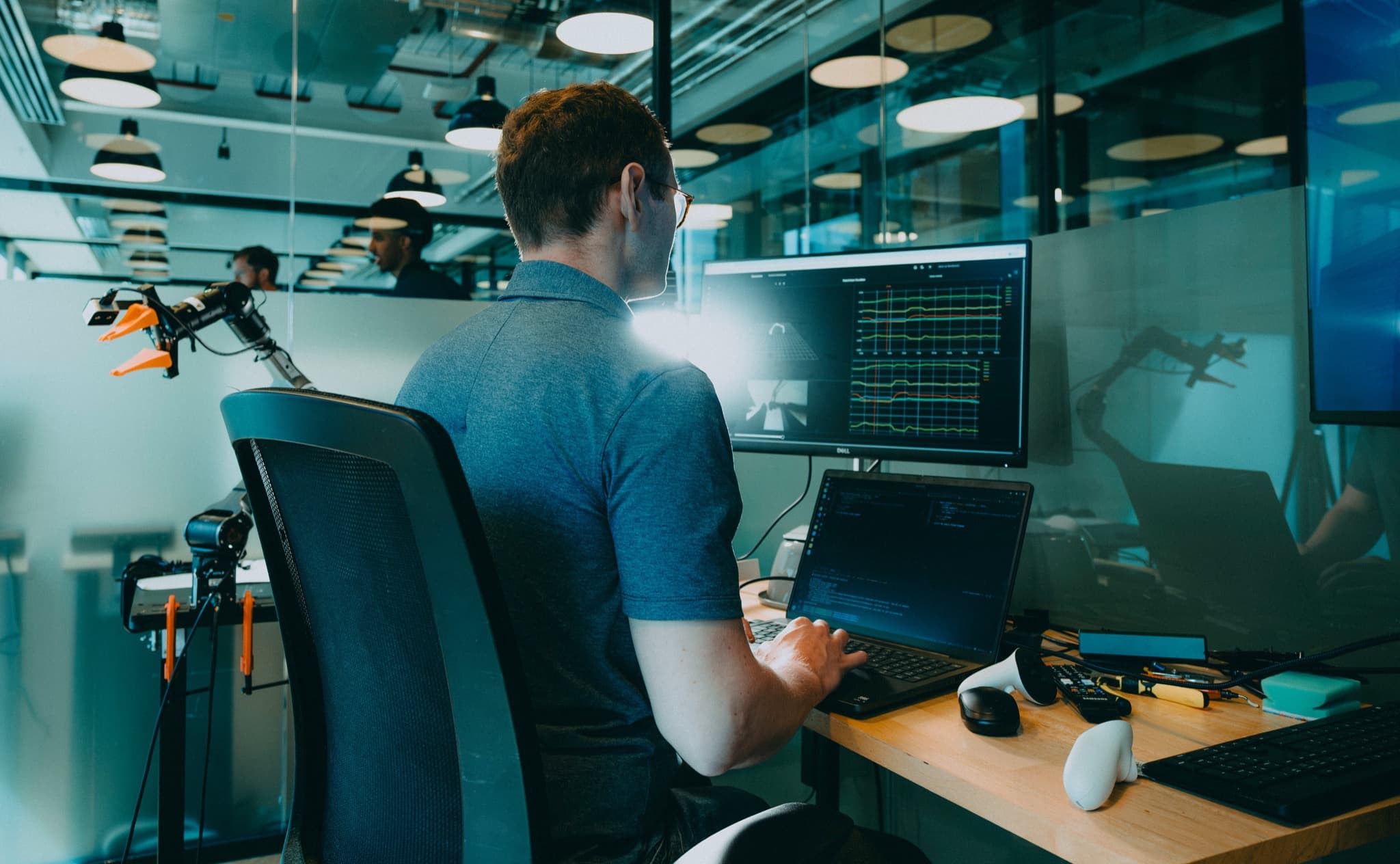 Engineer working at a Neuracore workstation with an AgileX robot arm and live data dashboards